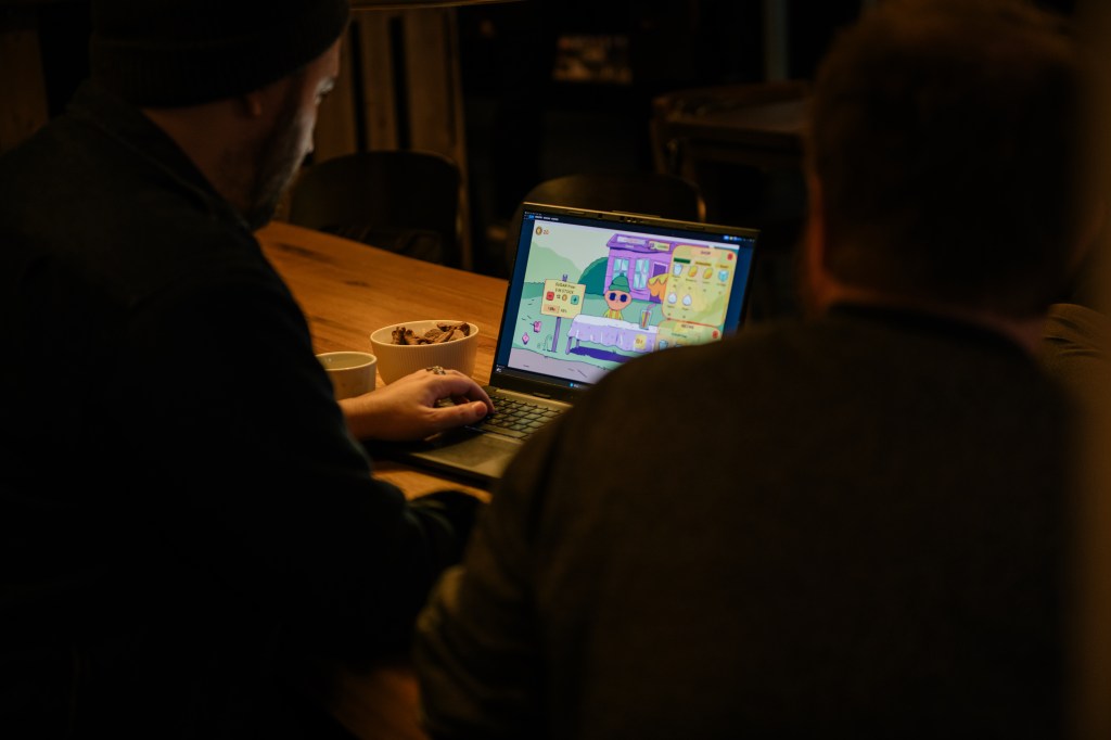 Bilde sett over skulderen på en utgiver som tester spillet, Lemonad Apocalypse som vises på skjermen i datamaskinen foran han.